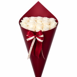 Bouquet of white roses wrapped in deep red paper with a ribbon