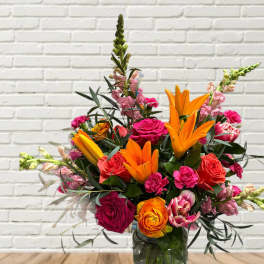 Bright mixed bouquet with orange lilies and pink roses in a glass vase