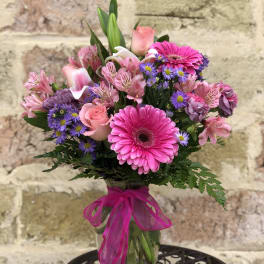 Pink and purple mixed bouquet in a glass vase with a ribbon