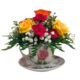 Bouquet of yellow and pink roses in a floral teacup and saucer