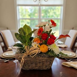 Basket arrangement with red roses, orange and white flowers, and a calla lily