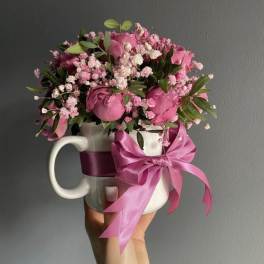 Pink rose bouquet in a white mug with a satin bow