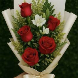 Bouquet of red roses and white flowers wrapped in cream paper with a ribbon