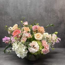 Pastel floral arrangement in a low vase with roses, hydrangeas, and carnations