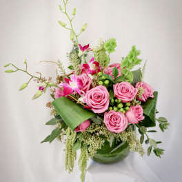 Pink roses and orchids arranged in a green vase