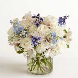 White and blue mixed bouquet in a clear glass vase