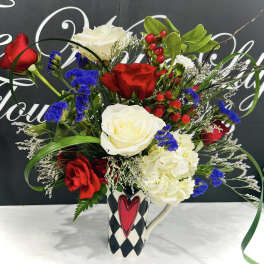 Bouquet of red and white roses with blue filler flowers in a patterned mug