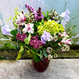 Mixed bouquet in a dark glass vase with pink, purple, and white blooms