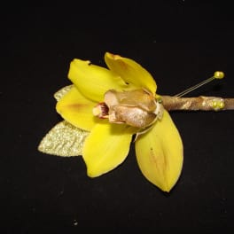 Yellow orchid boutonniere with gold ribbon on a black background