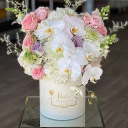 Pink and white floral arrangement in a white hat box