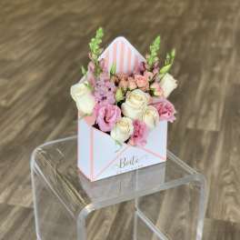Pink and white roses in a striped gift box arrangement