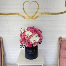 Pink rose arrangement in a navy cylindrical box with white orchids