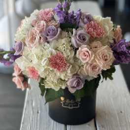 Lavender roses and white hydrangeas in a black hat box