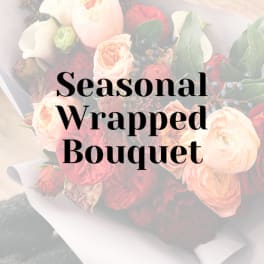 Wrapped bouquet of blush and red roses with greenery