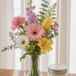 Mixed bouquet in a clear glass vase with pink, yellow, white, and purple flowers