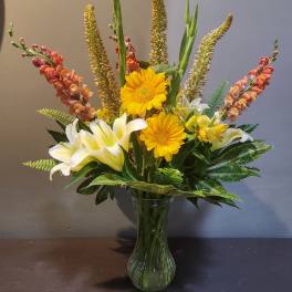 Mixed bouquet with yellow gerbera daisies and white lilies in a glass vase
