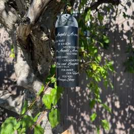Black memorial wind chime hanging from a tree branch