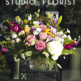 Mixed bouquet of pink roses, lilies, and white hydrangea in a glass vase