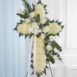 Standing cross of white flowers with white roses and ribbon on an easel