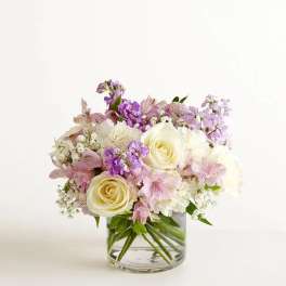 Low glass vase arrangement with cream roses, white blooms, and soft pink and lavender flowers