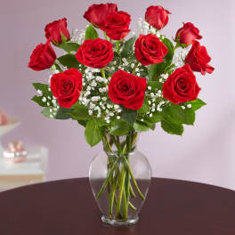 Red roses arranged in a clear glass vase with white baby's breath