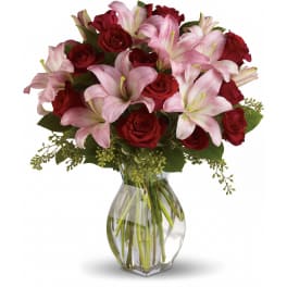 Arrangement of red roses and pink lilies in a clear glass vase with water