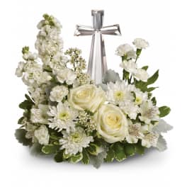 White sympathy arrangement with roses, carnations, and a crystal cross in a low container