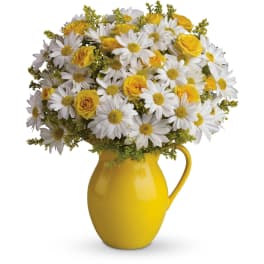 Yellow and white bouquet of daisies and roses in a bright yellow ceramic pitcher