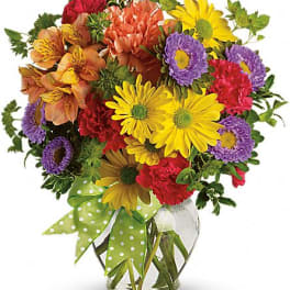 Colorful mixed bouquet in a clear glass vase with a polka-dot ribbon