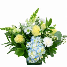 Yellow roses and blue hydrangeas in a glass vase