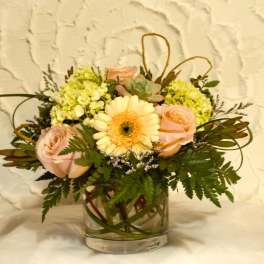 Bouquet of pale pink roses and a peach gerbera daisy in a glass vase