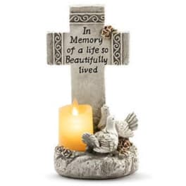Memorial cross with a lit candle and dove figurines