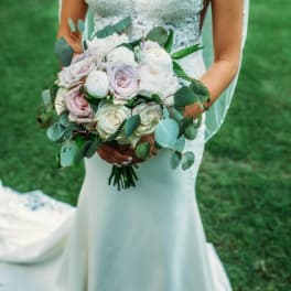 Bride holding a bouquet of pale roses and greenery