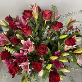 Bouquet of red roses and pink lilies with greenery