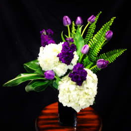 Purple tulips and white hydrangeas in a black vase