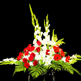 Tall floral arrangement with red roses, white lilies, and orange gerberas