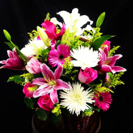 Pink and white mixed flower arrangement in a wicker basket
