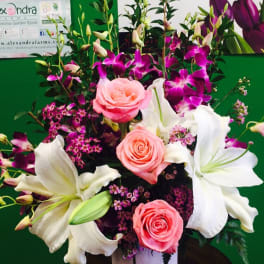 Pink roses and white lilies in a white vase with purple orchids