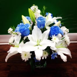 White lilies and blue roses in a glass vase