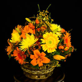 Basket arrangement of yellow and orange flowers with lilies and daisies