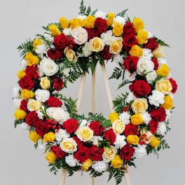 Circular wreath of red, yellow, and white roses on a wooden easel