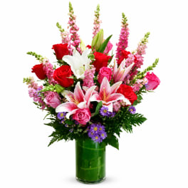 Bouquet of red and pink roses with white lilies in a green glass vase