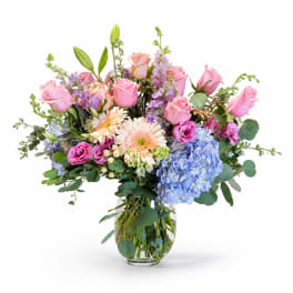 Mixed pink and blue flower arrangement in a clear glass vase
