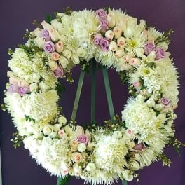 Large floral wreath of white and lavender blooms on a stand