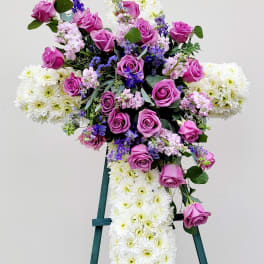 Cross-shaped floral spray with pink roses and white chrysanthemums on an easel