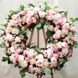 Large pink and white floral wreath on a wooden stand