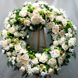 Large white floral wreath on a wooden stand