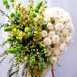 Large floral standing spray with white roses and green orchids on an easel