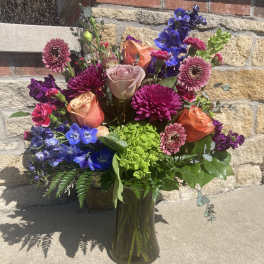 Colorful mixed bouquet in a glass vase with roses and blue flowers