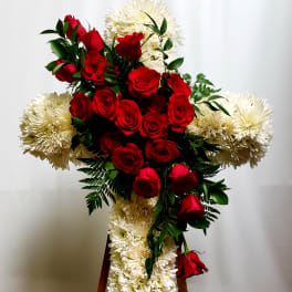 Red roses and white chrysanthemums arranged in a cross on a stand